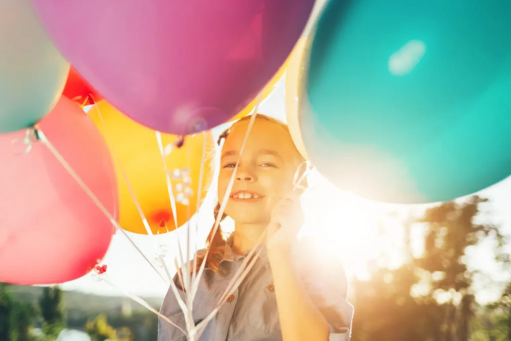 Criança sorrindo entre balões coloridos – ideias de decoração com balões para festas alegres