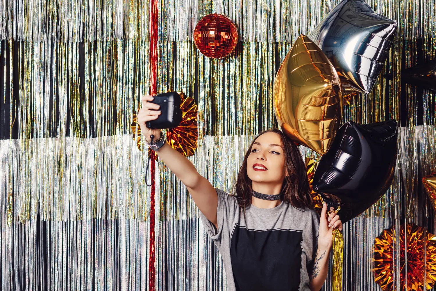 Mulher fazendo selfie com balões coloridos em festa, ilustrando algumas das ideias de festas